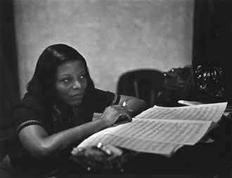 Mary Lou Williams with sheet music, listening to someone out of frame